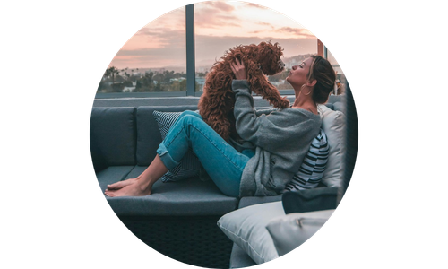 Woman playing with a dog on a couch with a scenic background
